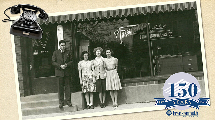 An old black and white photograph of one man and three women standing in front of storefront window that reads, "Frankenmuth Mutual Fire Insurance Company."