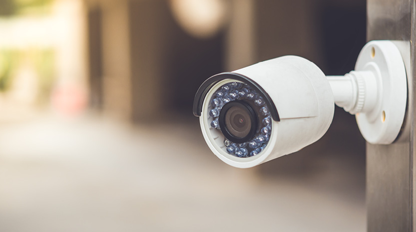 A close-up photo of a white security camera mounted to a wall.